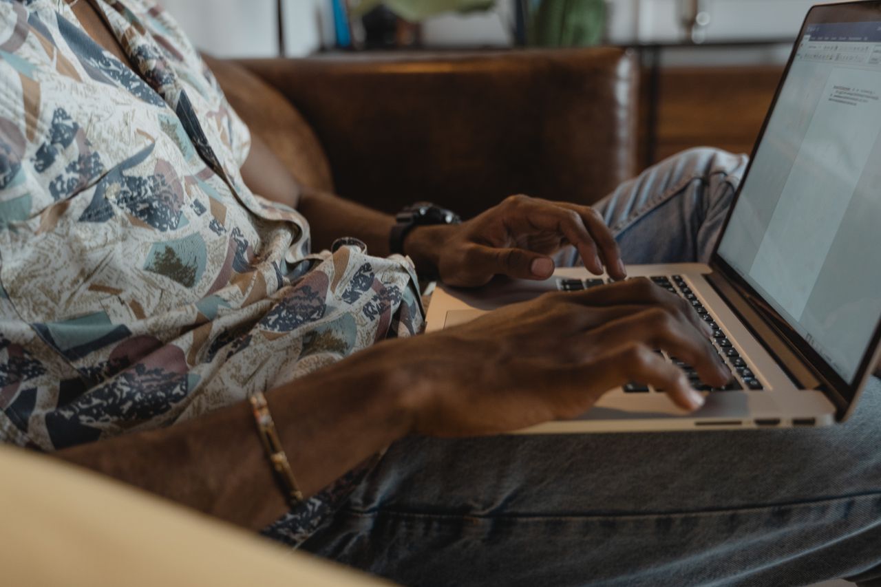 Close-up of individual typing on a laptop indoors, ideal for remote work or online learning themes.